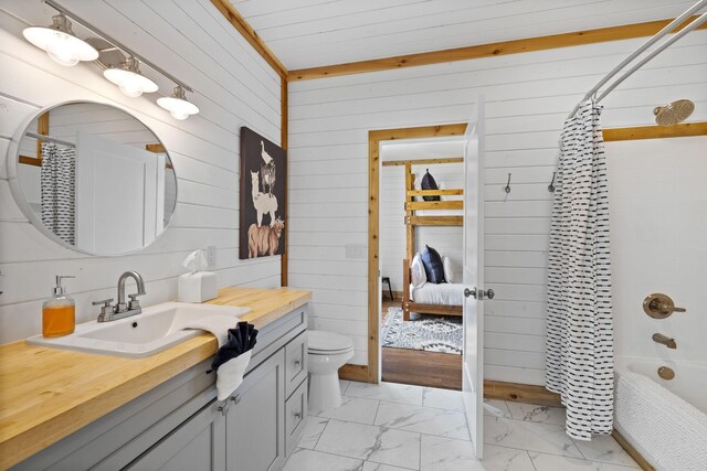 bathroom featuring vanity, wood walls, marble finish floor, toilet, and shower / bathtub combination with curtain