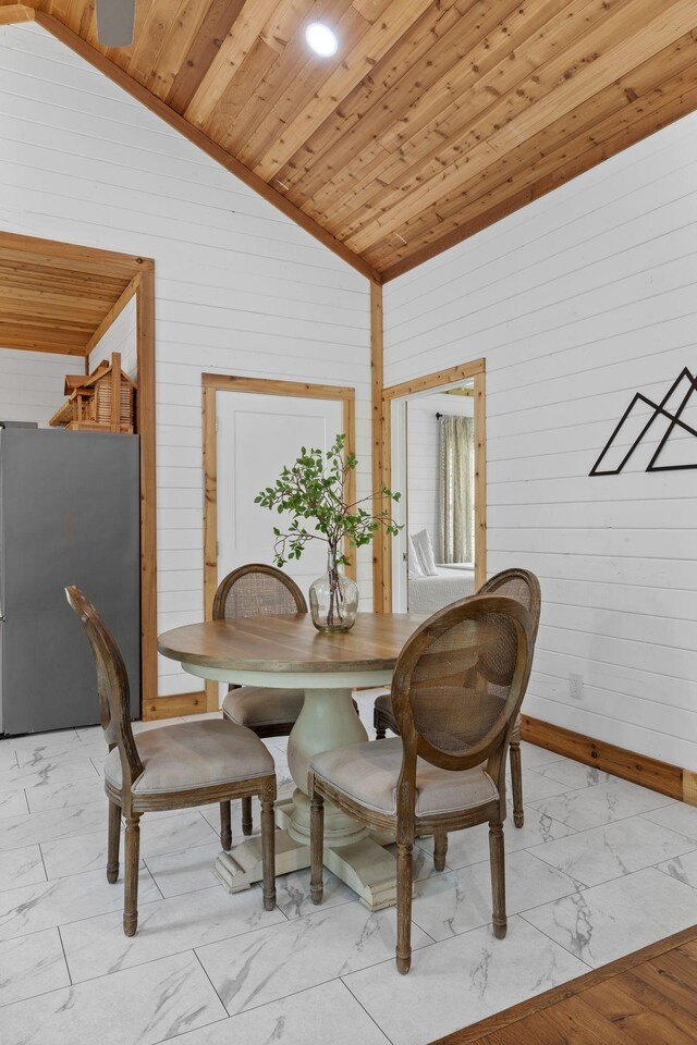 dining space featuring wood walls, lofted ceiling, wood ceiling, and marble finish floor
