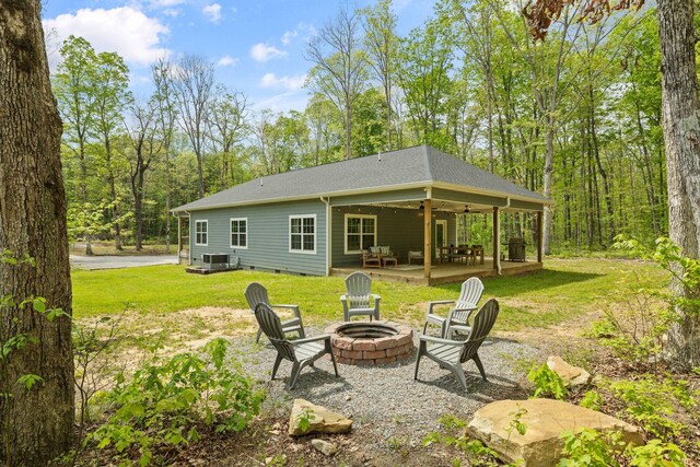 back of house with a ceiling fan, roof with shingles, a yard, a patio, and a fire pit