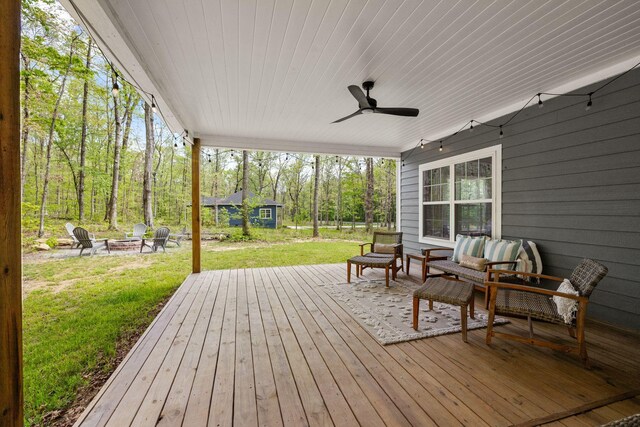 wooden terrace with ceiling fan, a yard, and a fire pit