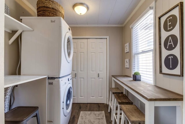 washroom featuring crown molding, stacked washer / drying machine, dark wood-type flooring, and laundry area