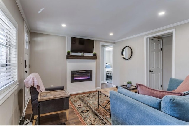 living area with crown molding, wood finished floors, baseboards, a glass covered fireplace, and recessed lighting