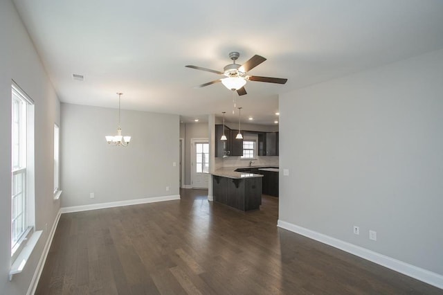 unfurnished living room featuring visible vents, baseboards, ceiling fan with notable chandelier, recessed lighting, and dark wood-type flooring