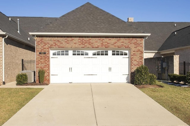 view of side of home featuring roof with shingles, central AC unit, concrete driveway, and brick siding