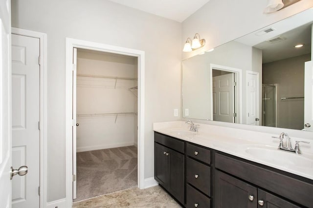 bathroom with visible vents, a sink, double vanity, and a shower stall