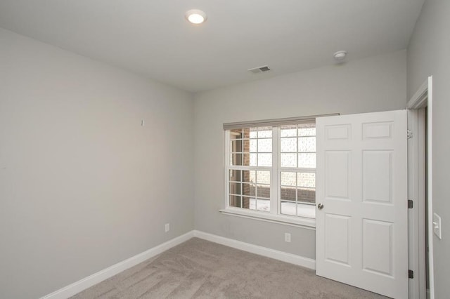 spare room featuring baseboards, visible vents, and light colored carpet