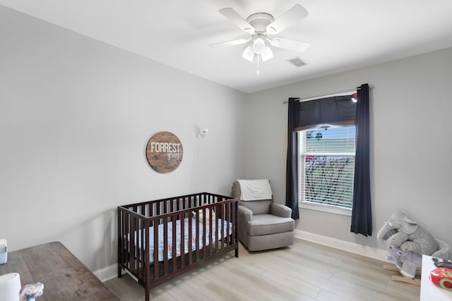 bedroom with baseboards, wood finished floors, and a nursery area