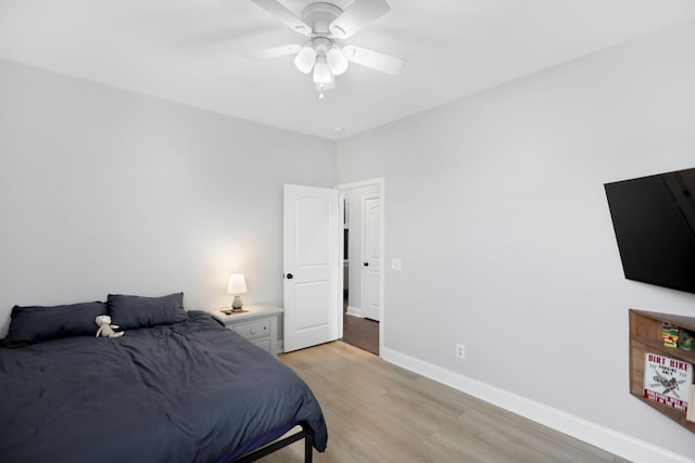 bedroom with a ceiling fan, baseboards, and light wood finished floors