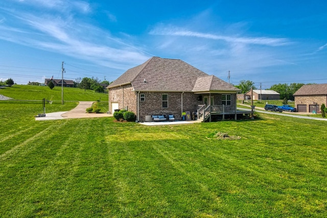 rear view of property featuring a patio, a shingled roof, a yard, and brick siding
