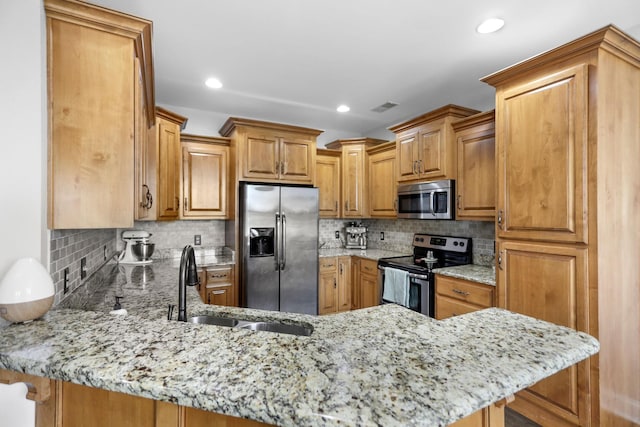 kitchen with appliances with stainless steel finishes, light stone countertops, a peninsula, and visible vents