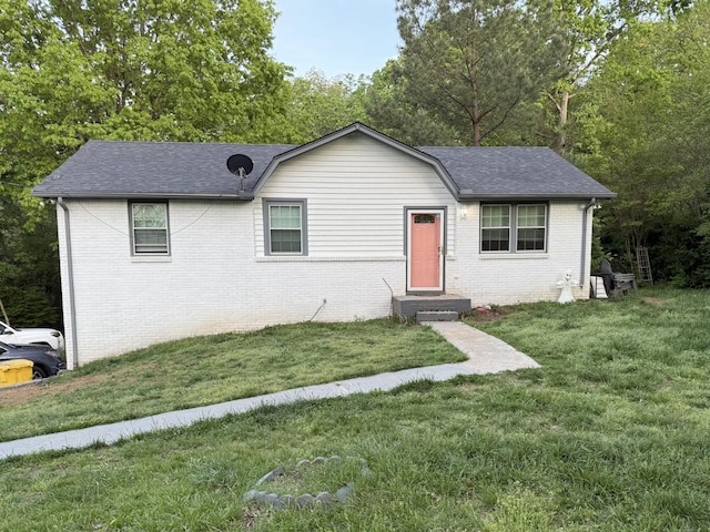 single story home with roof with shingles, entry steps, brick siding, and a front yard