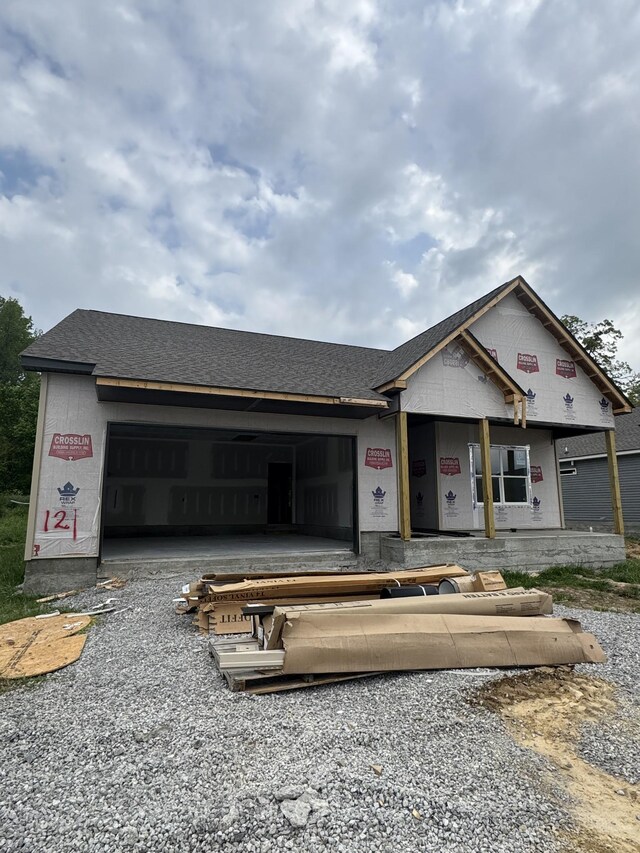 unfinished property with a shingled roof and an attached garage