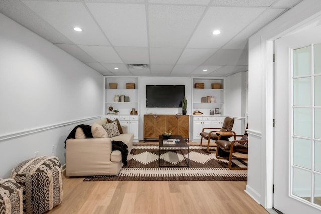 living room featuring visible vents, recessed lighting, a paneled ceiling, built in shelves, and light wood-style flooring