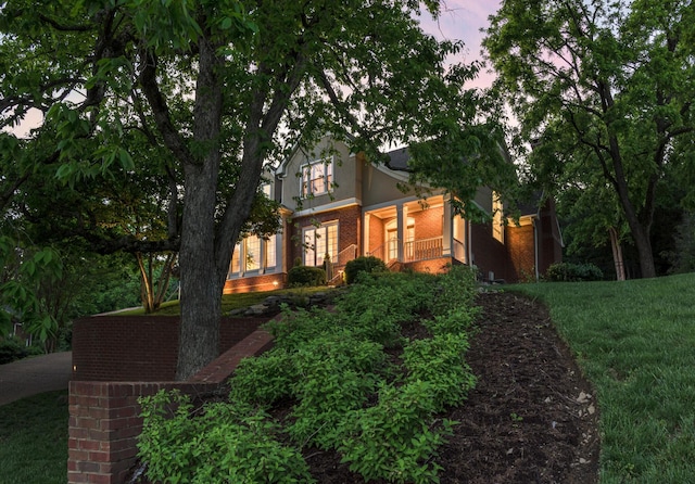 view of side of property featuring stucco siding, a yard, and brick siding