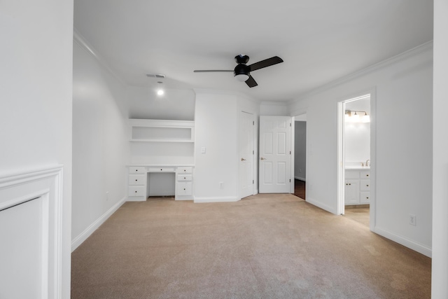 unfurnished bedroom featuring crown molding, light colored carpet, built in desk, baseboards, and visible vents