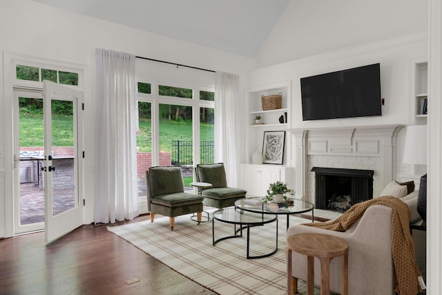 living area featuring built in features, a brick fireplace, wood finished floors, and a wealth of natural light