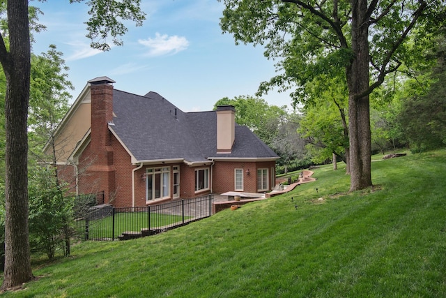 rear view of house featuring a chimney, a lawn, brick siding, fence, and a patio