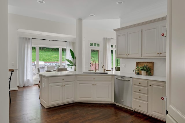 kitchen with dark wood-style flooring, stainless steel dishwasher, a sink, light countertops, and a peninsula