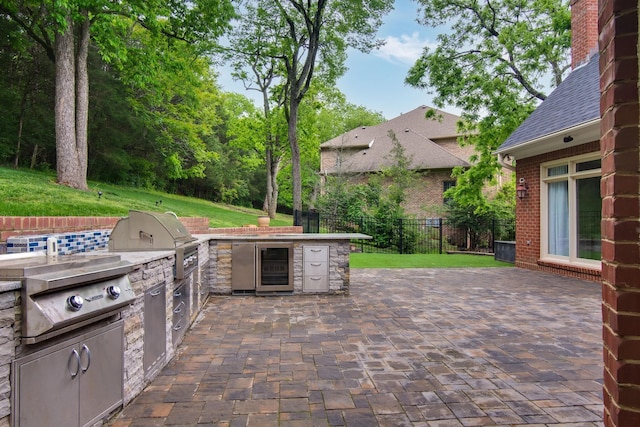 view of patio with beverage cooler, fence, area for grilling, and an outdoor kitchen