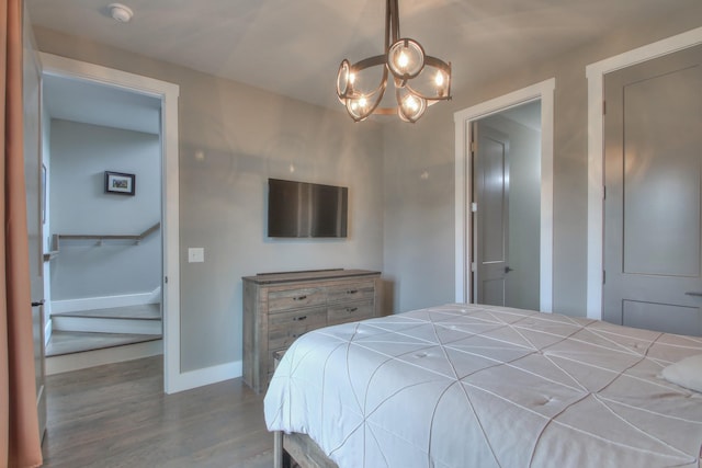 bedroom with baseboards, wood finished floors, and a chandelier