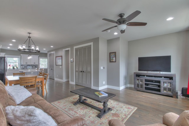 living area with baseboards, recessed lighting, dark wood-style flooring, and ceiling fan with notable chandelier