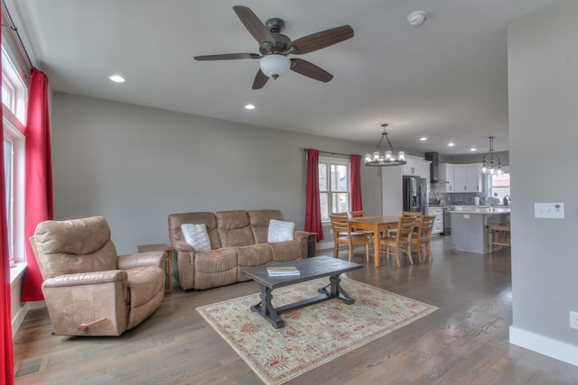 living room featuring dark wood-style flooring, ceiling fan with notable chandelier, and recessed lighting
