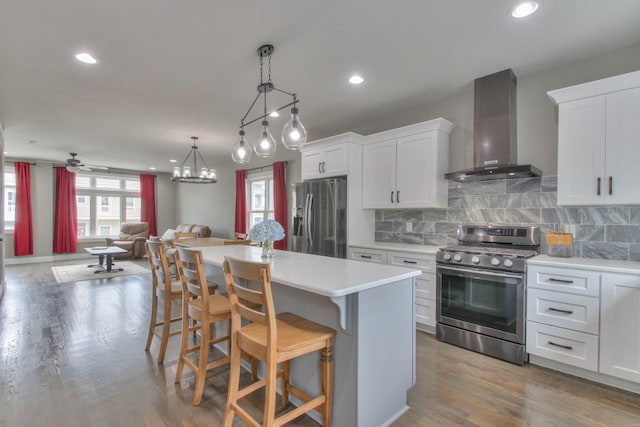kitchen featuring appliances with stainless steel finishes, wall chimney exhaust hood, light countertops, open floor plan, and white cabinetry