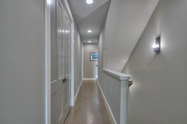 hall featuring recessed lighting, baseboards, wood finished floors, and an upstairs landing