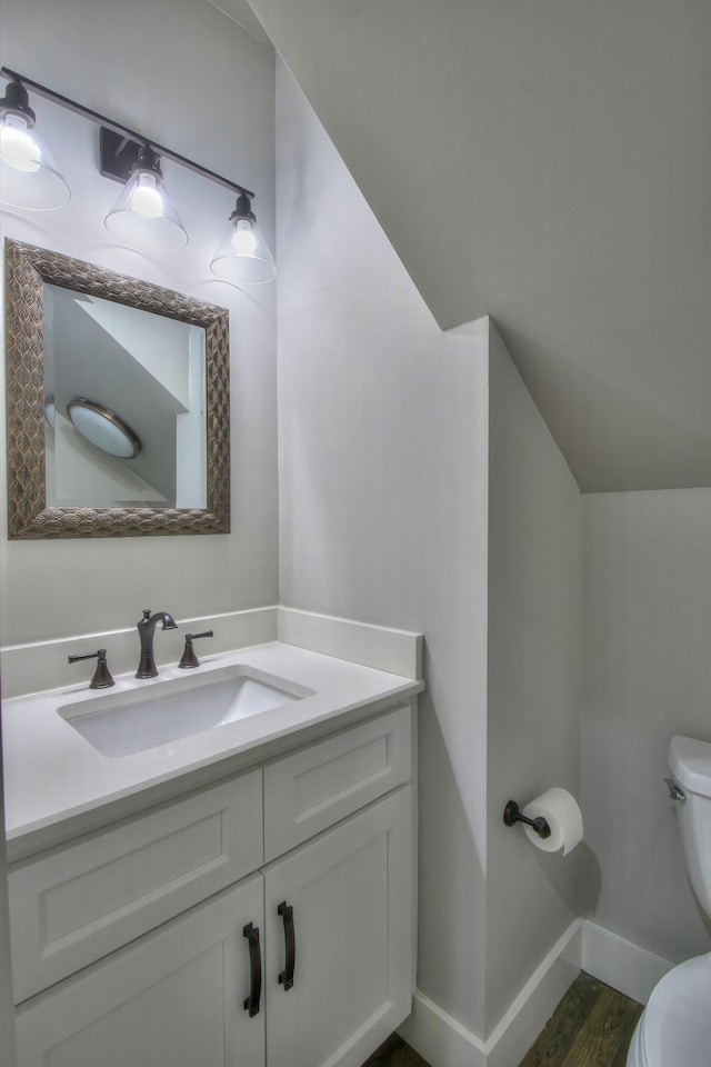 bathroom featuring toilet, baseboards, wood finished floors, and vanity