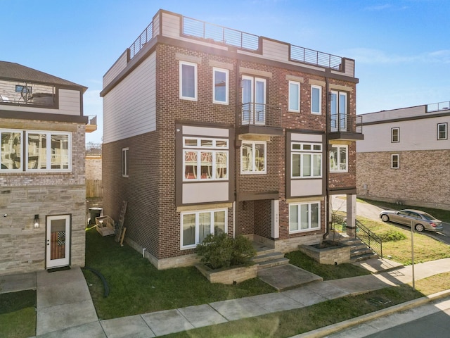 view of front of house with brick siding and a balcony