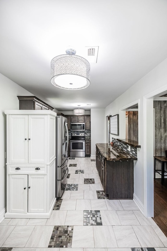 907 N Graycroft Ave, Madison, TN 37115 - kitchen featuring appliances with stainless steel finishes, dark countertops, baseboards, and dark brown cabinets