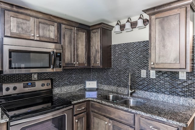 907 N Graycroft Ave, Madison, TN 37115 - kitchen with stainless steel appliances, a sink, dark brown cabinets, backsplash, and dark stone counters