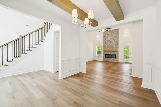 1065 Gholson Rd, Clarksville, TN 37043 - unfurnished living room featuring stairs, beamed ceiling, light wood-style floors, a stone fireplace, and ceiling fan with notable chandelier