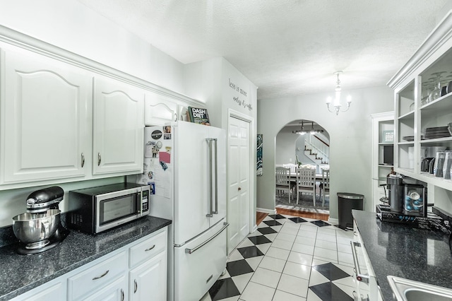 1505 Newmans Trl, Hendersonville, TN 37075 - kitchen with light tile patterned flooring, white cabinetry, stainless steel microwave, arched walkways, and a notable chandelier