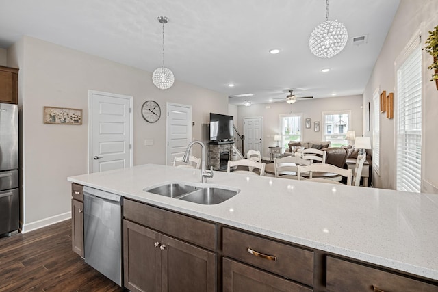 kitchen featuring a sink, dark wood finished floors, stainless steel appliances, decorative light fixtures, and visible vents