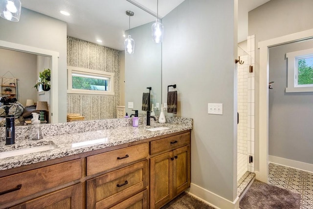full bathroom with double vanity, baseboards, a sink, and a stall shower