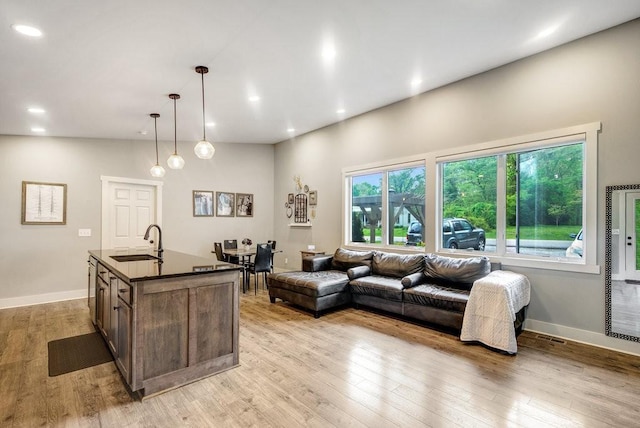 living area featuring baseboards, light wood finished floors, and recessed lighting