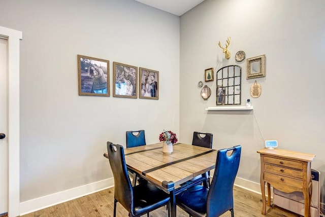 dining space with baseboards and light wood-style flooring