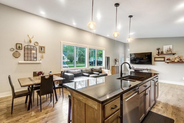 kitchen with dark countertops, a sink, light wood-style floors, and dishwasher