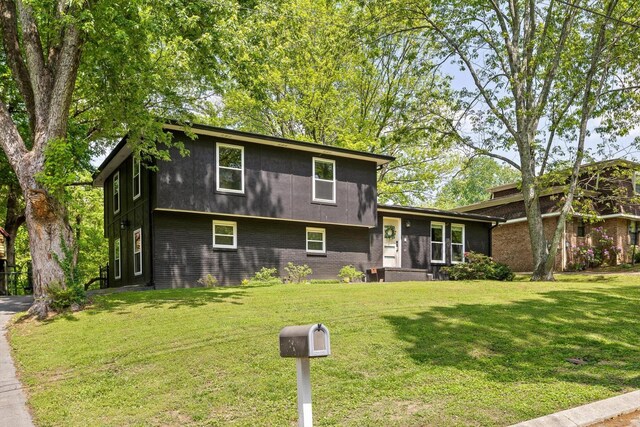 tri-level home featuring brick siding and a front yard