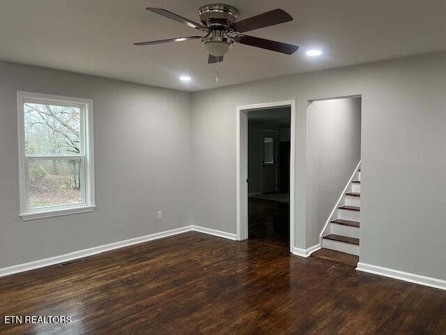 empty room with baseboards, stairway, ceiling fan, and wood finished floors