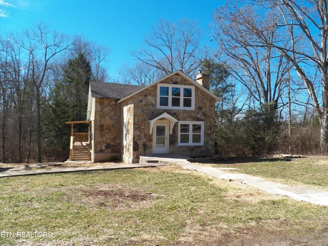 view of front of house with a chimney, stone siding, and a front yard