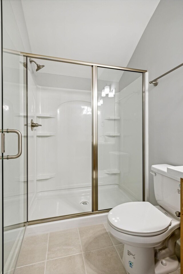 bathroom with tile patterned flooring, a stall shower, and toilet