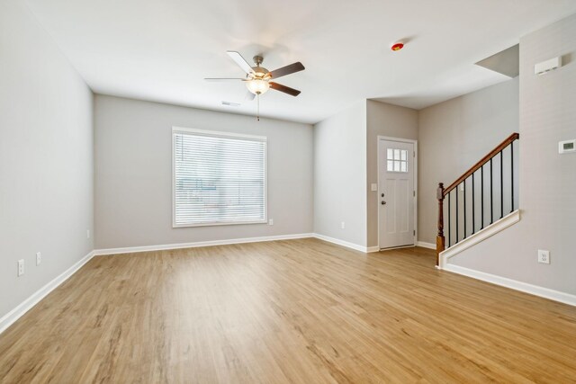 unfurnished living room with light wood-style floors, stairs, ceiling fan, and baseboards