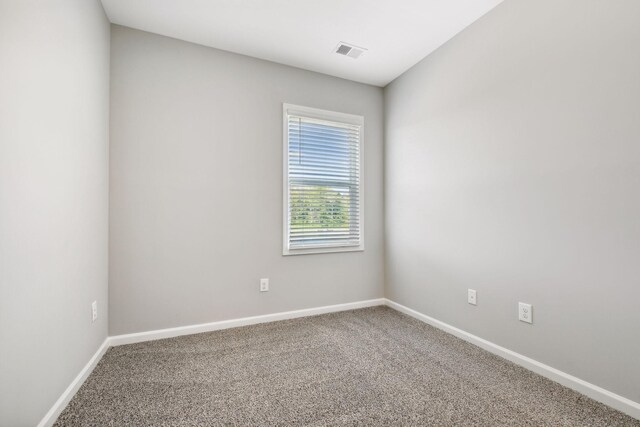 carpeted spare room featuring visible vents and baseboards