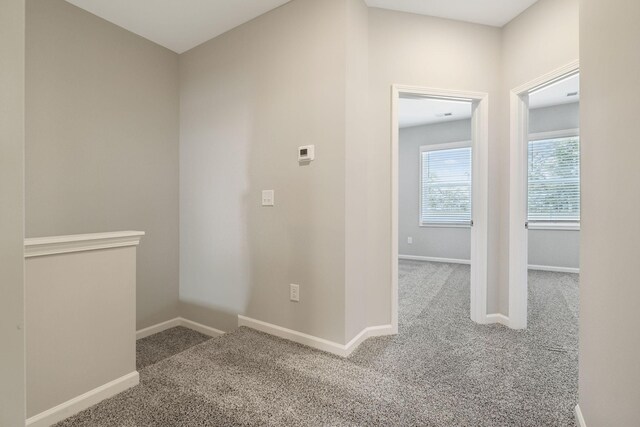 hall featuring carpet flooring and baseboards