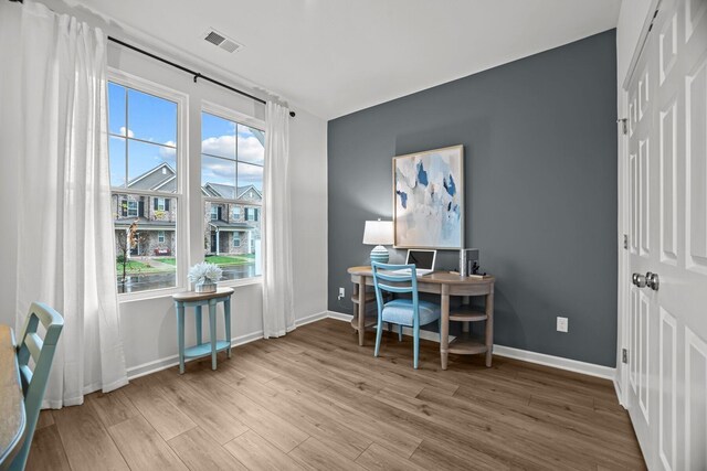 office area featuring a healthy amount of sunlight, baseboards, wood finished floors, and visible vents