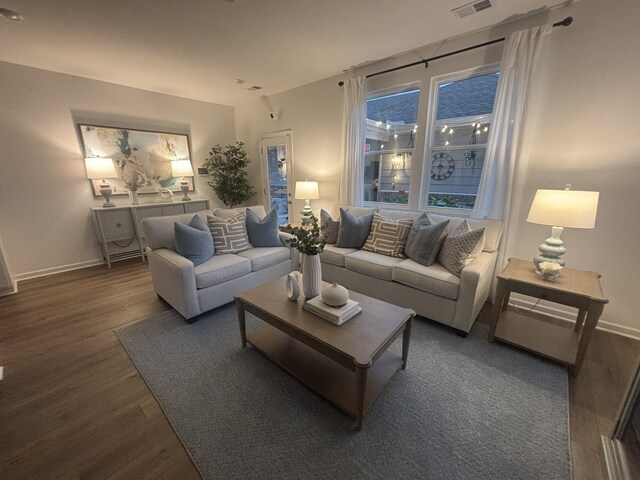 living area with baseboards, visible vents, and wood finished floors