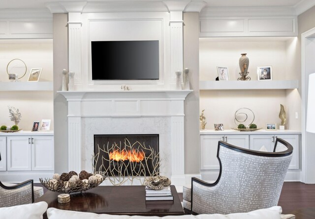 interior space featuring crown molding, built in features, a fireplace, and dark wood-style floors