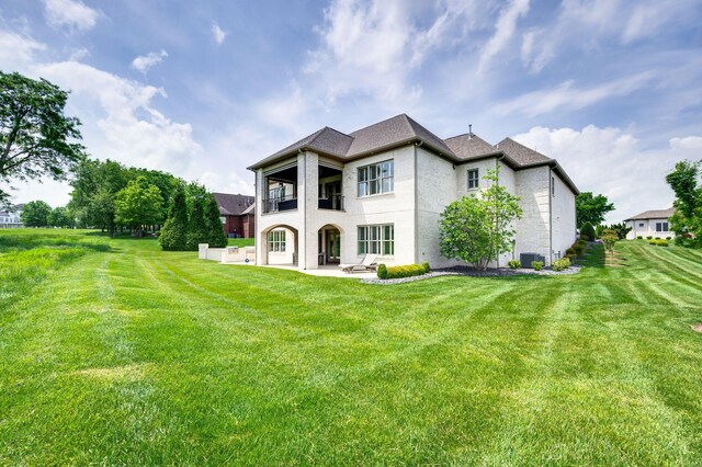 rear view of house featuring a yard, a patio, and a balcony